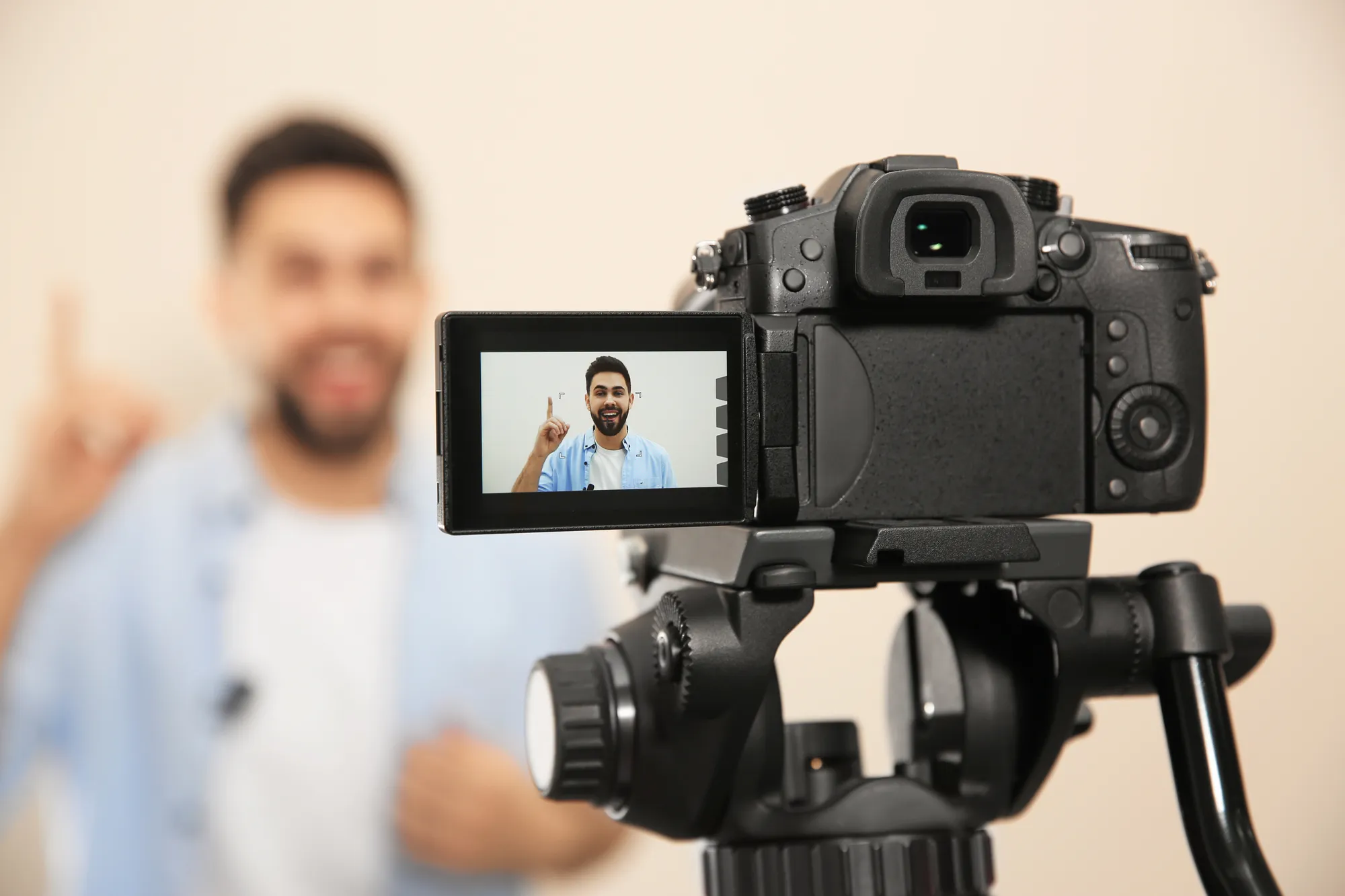 Digitale camera op statief met LCD-scherm waarop een mannelijke spreker in beeld is die een video opneemt.